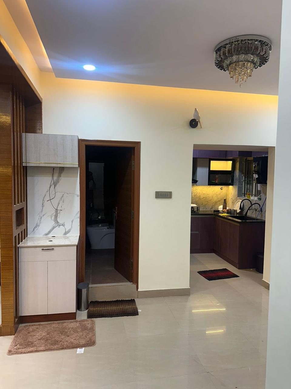Finished apartment passage with utility cabinet and warm modular kitchen in the background