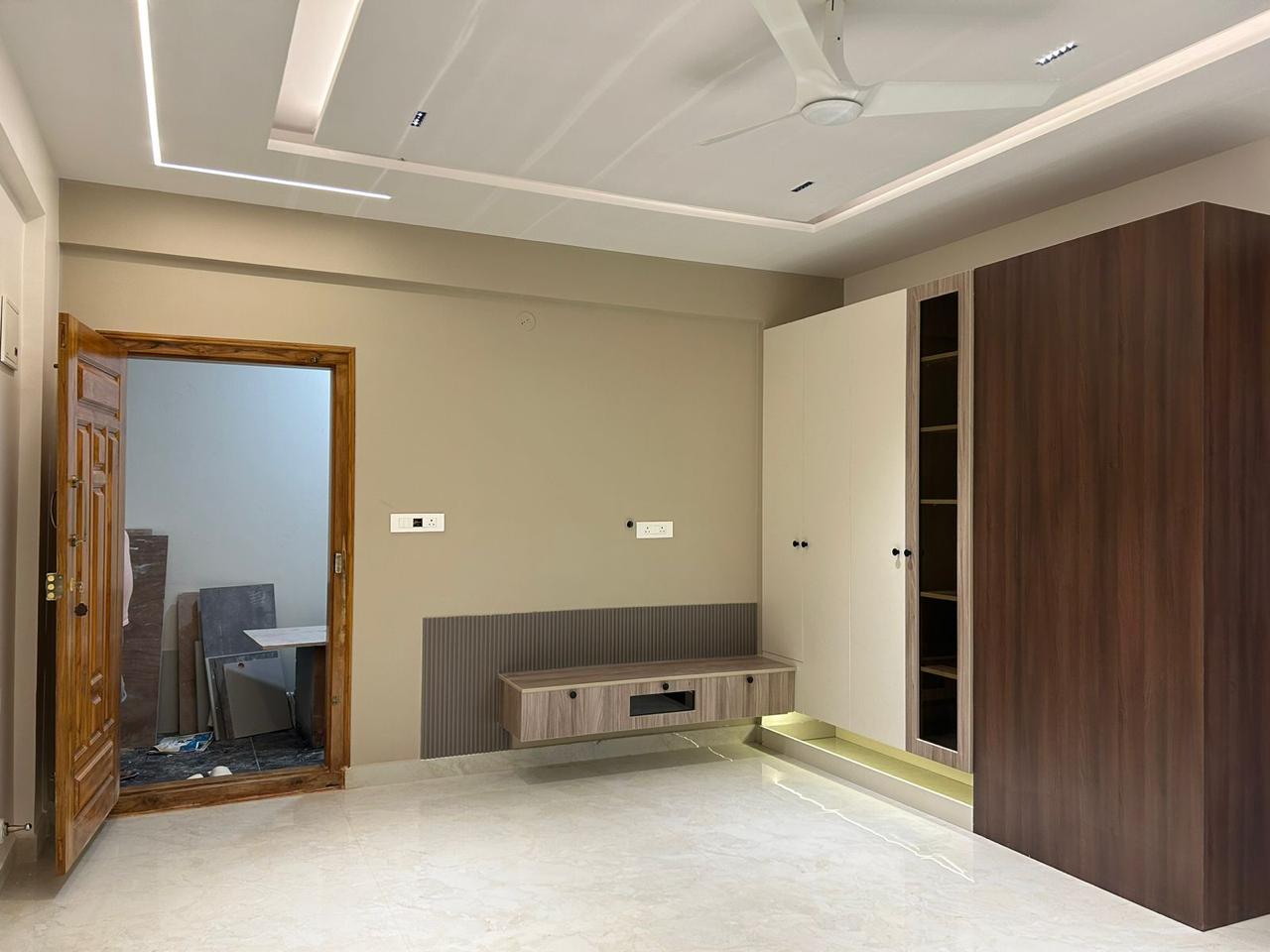 Finished bedroom with walnut and cream wardrobe floating TV console and recessed ceiling lights