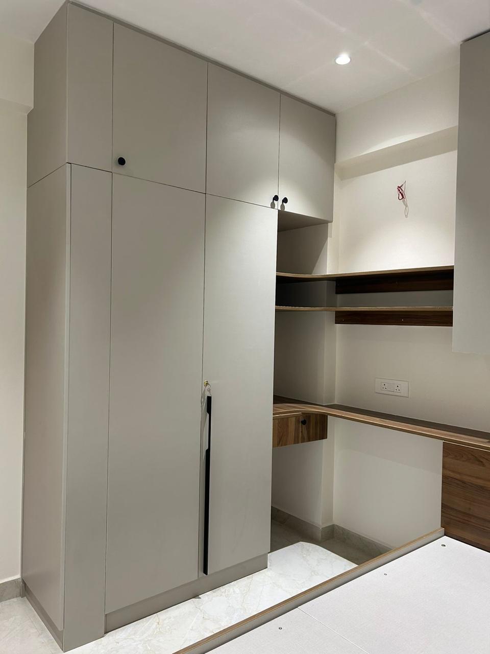 Finished bedroom storage wall with tall wardrobe and integrated study desk