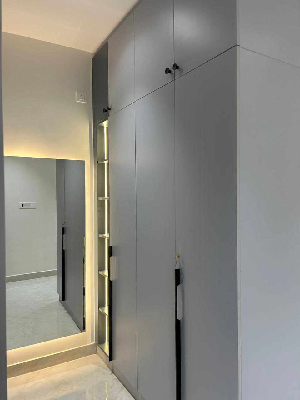 Finished grey wardrobe detail with full height mirror vertical display shelving and long black handles