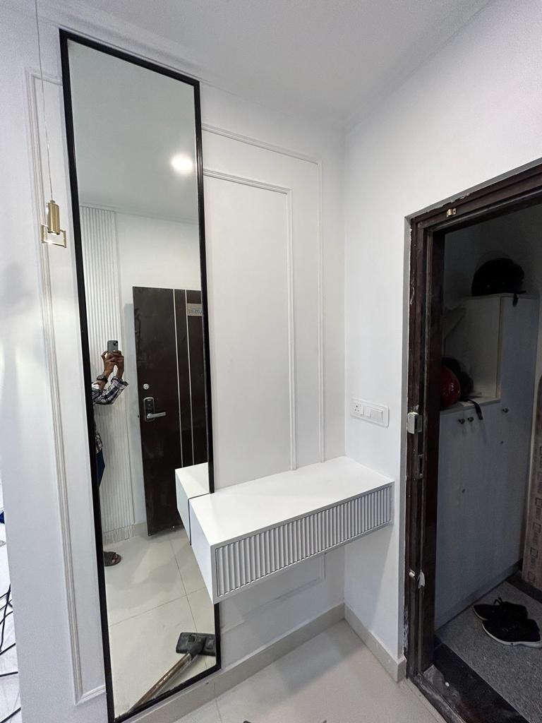 Elegant white entry console with fluted drawer and a tall vertical mirror on a paneled wall